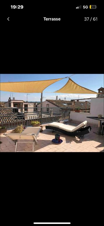 ein großer Sonnenschirm, eine Bank und Stühle in der Unterkunft Villa Colonia in Campofilone