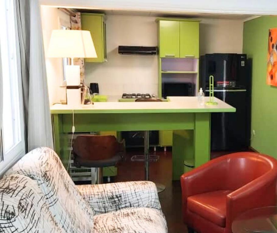 a living room with a kitchen with green cabinets at Appartement Soleil,Batterie 4 in Libreville