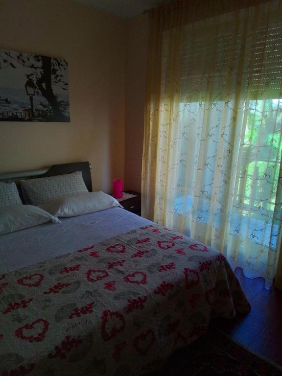 a bedroom with a bed and a window with curtains at Sul Lungo lago da Tatiana B&B in Dagnente