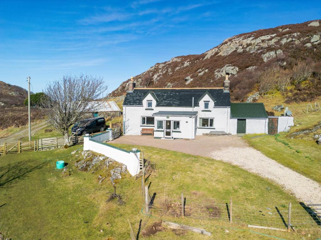 a white house with a hill in the background at Achloist Holiday Cottage in Drumbeg