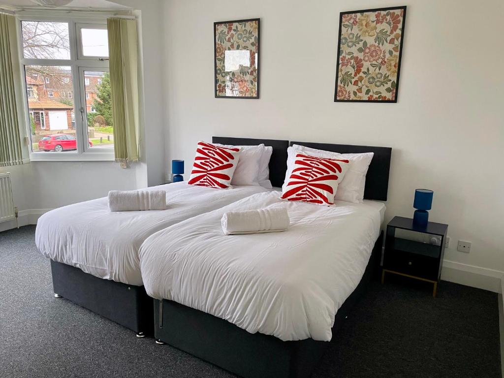 a bedroom with two beds with red and white pillows at University View-Off-Street Parking-Sleeps 8-Fast WiFi in Nottingham