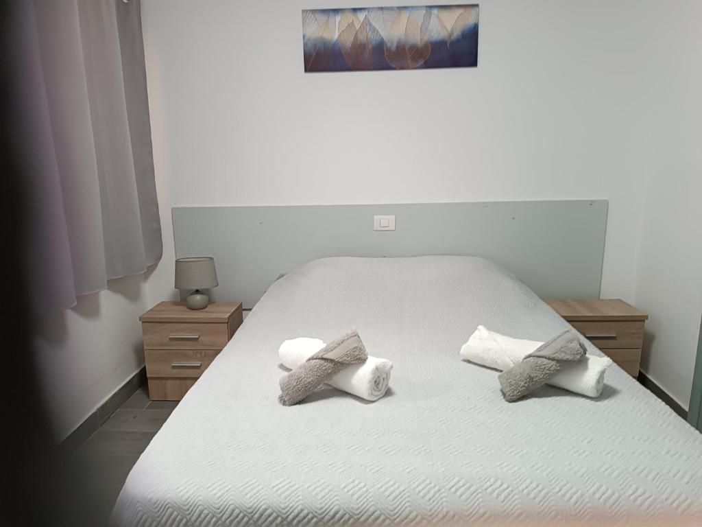 Una cama blanca con tres almohadas. en Elcorralito, en Corralejo