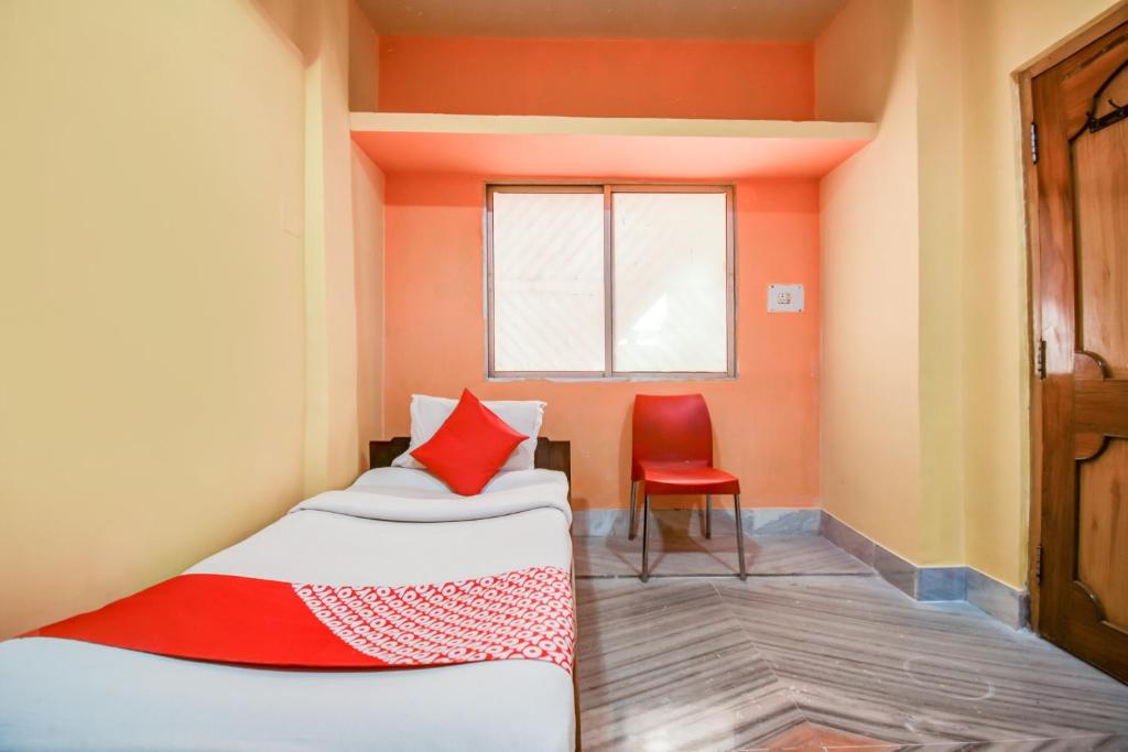 Habitación con 2 camas y silla roja. en Super OYO Hotel Priyal Amrit Sagar, en Rourkela