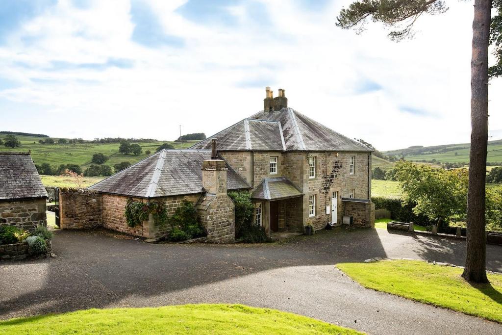an old stone house with a large driveway at Broadgate House & Steading in West Woodburn