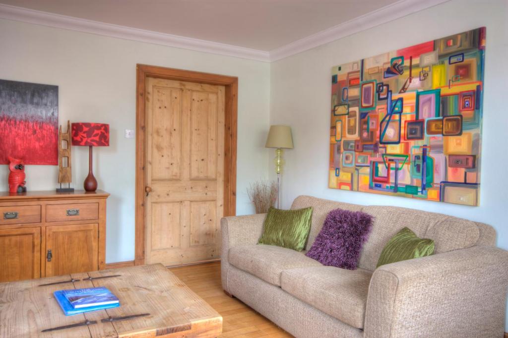 a living room with a couch and a painting on the wall at The Apartment at Allt-Sagart in Golspie