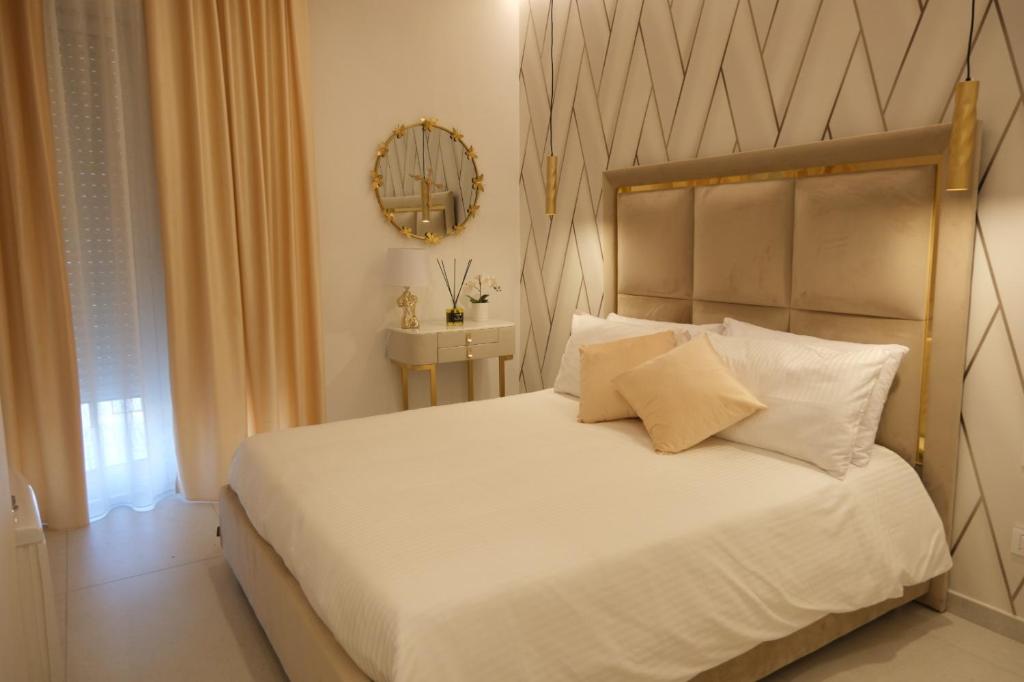 Un dormitorio con una cama blanca y un espejo. en Luxury Masaniello, en Nápoles