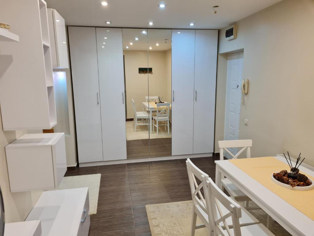 cocina con armarios blancos, mesa y sillas en Luxury Large Family Apartment en Zalău