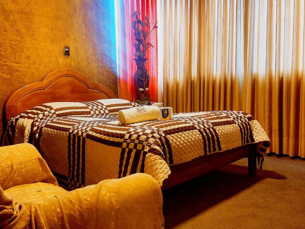 a bedroom with a bed with a blanket and a chair at HOTEL MIRADOR DE LOS ANDES in La Paz