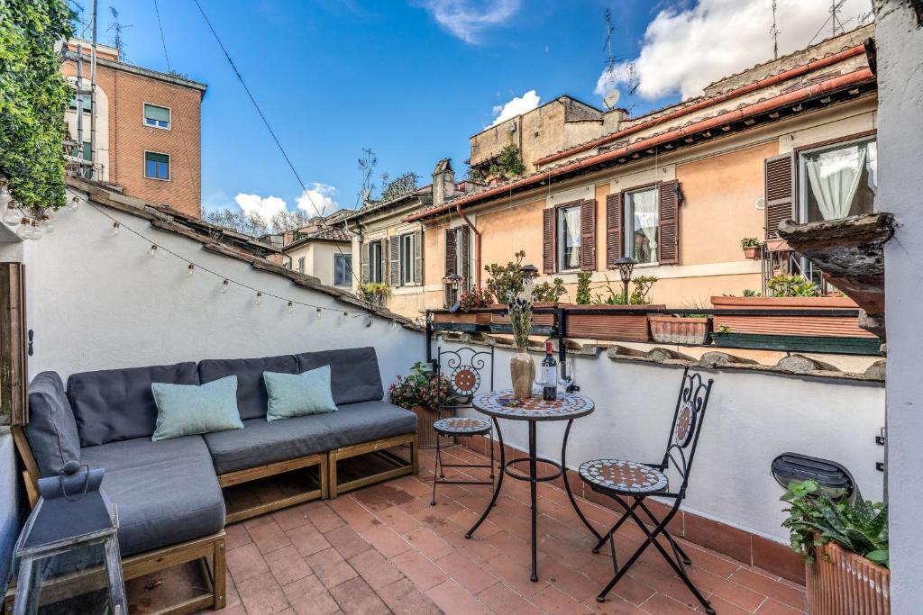 a balcony with a couch and a table and chairs at MAYA RHOME TRASTEVERE in Rome