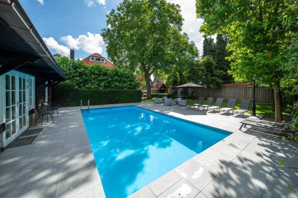 a swimming pool with blue water in a yard at Hush Bed & Breakfast in Helmond