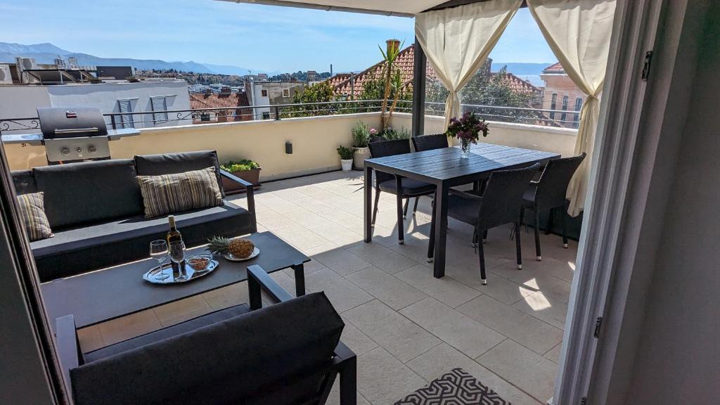 een balkon met een tafel, een bank en een tafel bij Prime Location Penthouse apt with a large terrace in Split