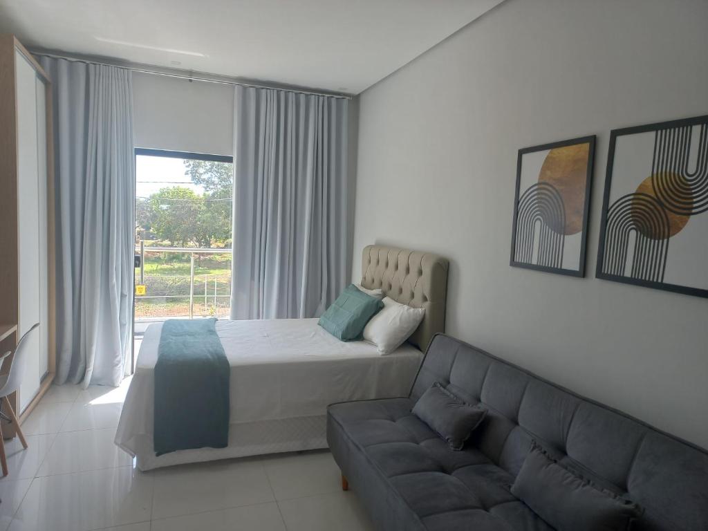 um quarto com uma cama e um sofá em apto. moderno, perto faculdades ulbra e católica. em Palmas
