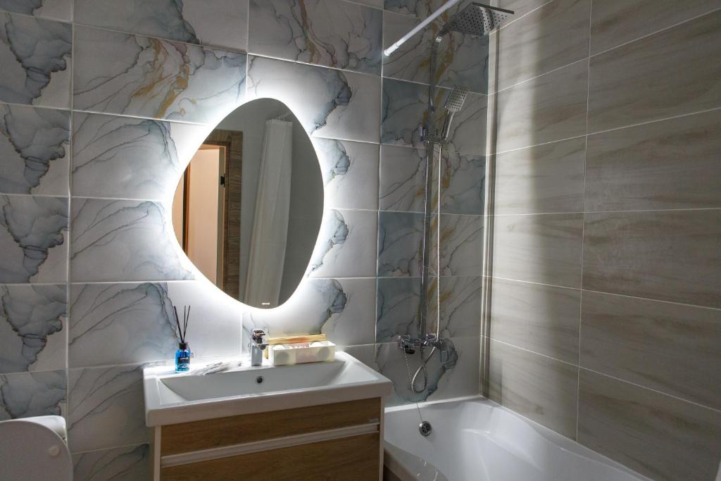 a bathroom with a sink and a mirror and a tub at Astana arena ЖК Бухар Жырау in Taldykolʼ