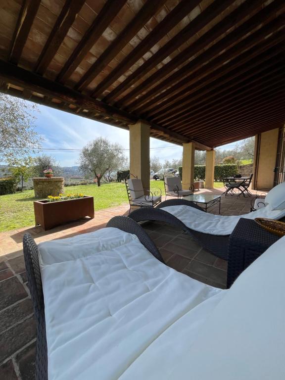 a patio with two beds under a wooden roof at Villa Mary, relax with swimming pool in Poggibonsi
