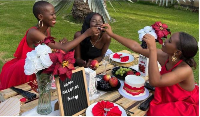 three women taking a picture of a table with a cake at Sinda Island Kigamboni Camping in Dar es Salaam
