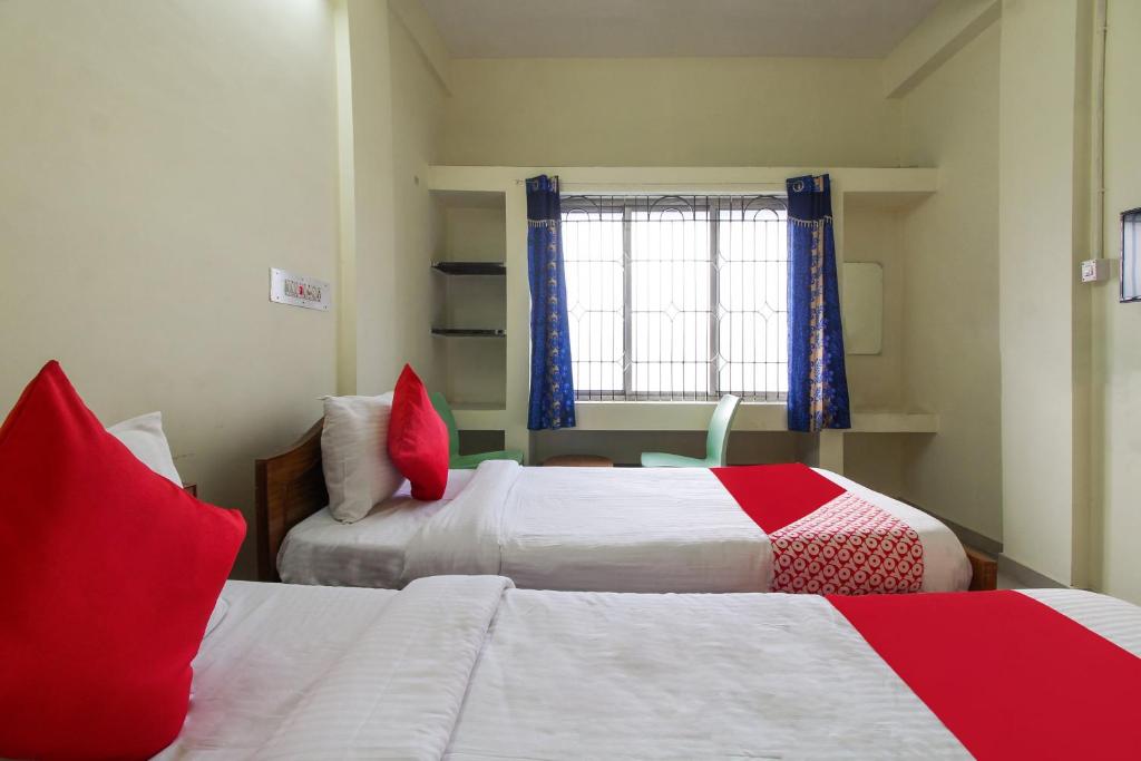 a bedroom with two beds with red pillows and a window at OYO Royal Residency in Sūramangalam