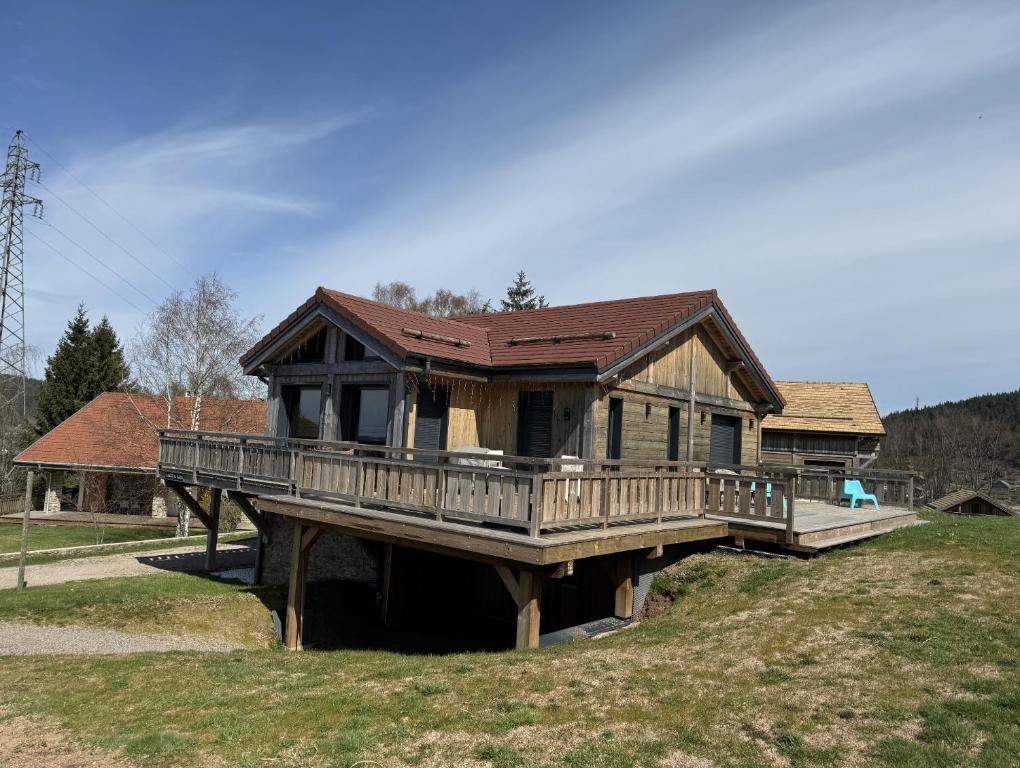 a large house with a deck on a field at L'ADRET DU TEMPS CHALET 10 PERSONNES 170m2 in Gérardmer