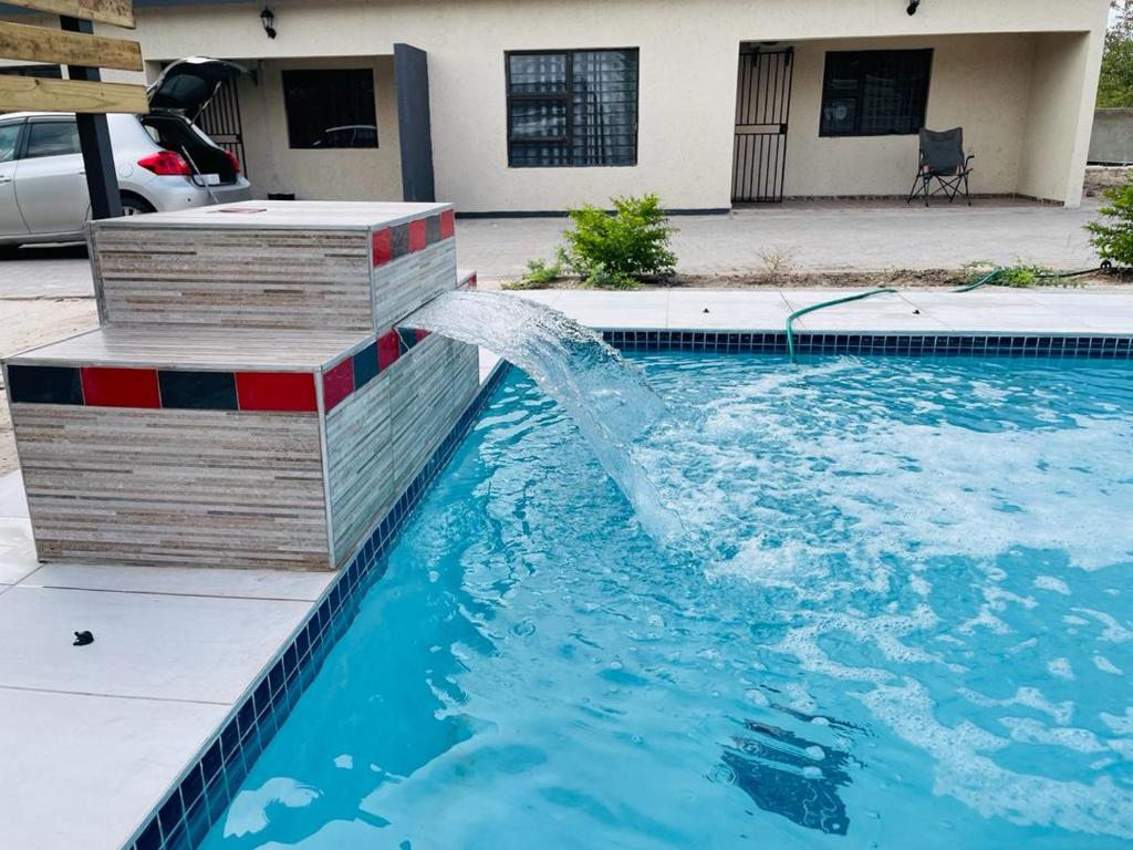 a pool with a water fountain in front of a house at Rocksie Apartments in Maun