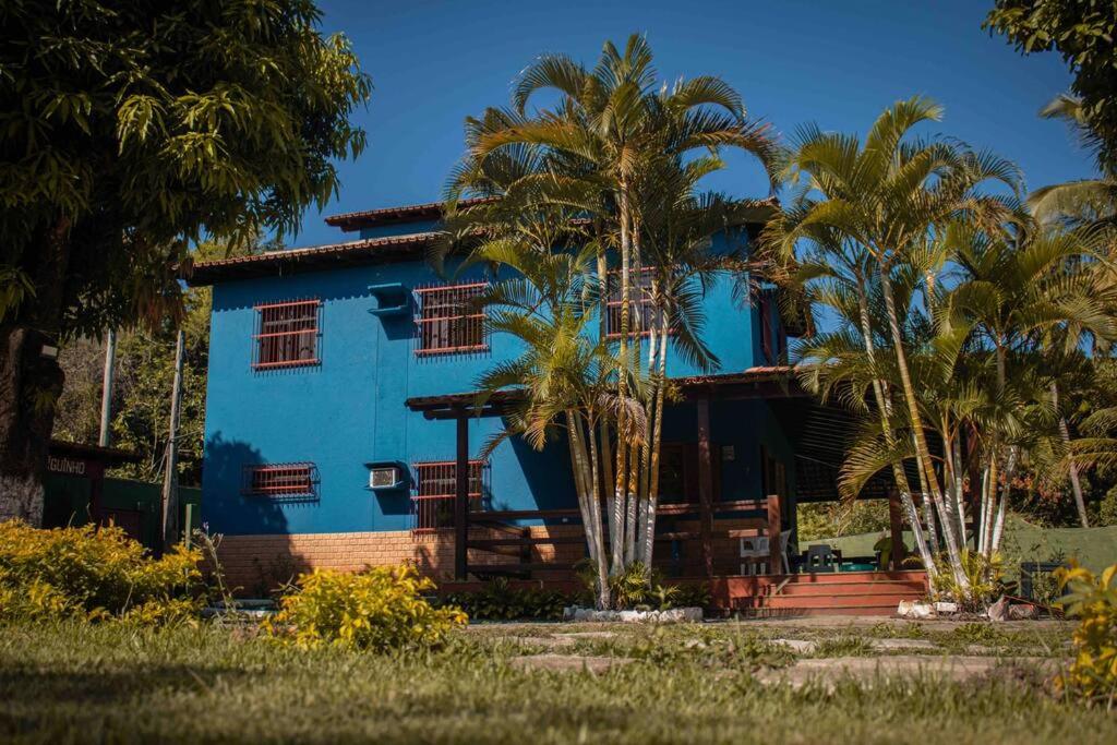 une maison bleue avec des palmiers devant elle dans l'établissement Recanto do Amiguinho, à Vila Velha