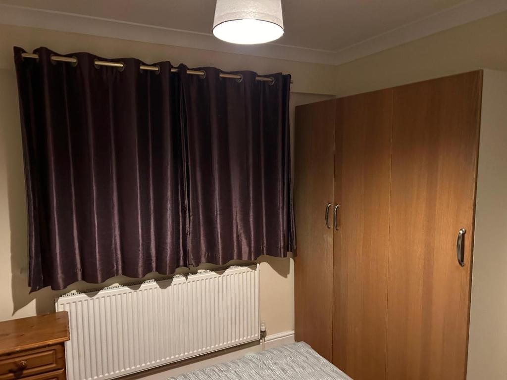 1 dormitorio con cortinas negras y radiador en Sw17 7ls en Londres