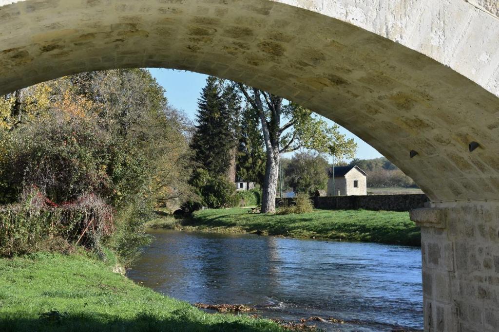 a bridge over a river with a river underneath it at Joli hébergement de caractère en bord de rivière in Saint-Vincent-sur-lʼIsle
