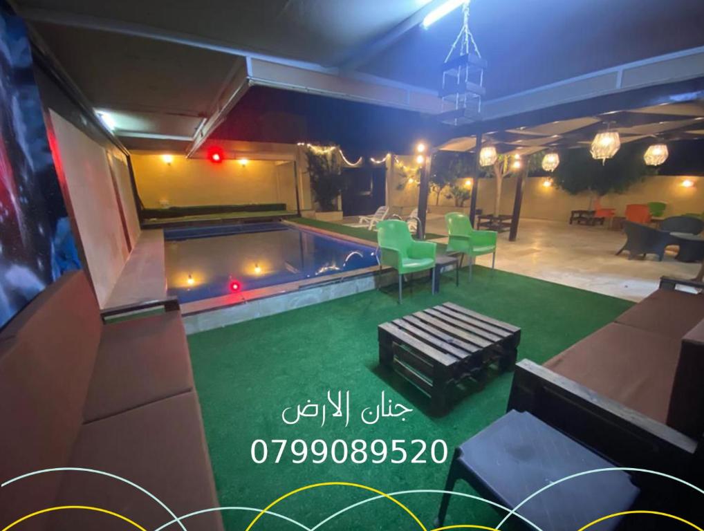 een kamer met een zwembad met groen gras bij شاليه جنان الارض in Al Kafrayn