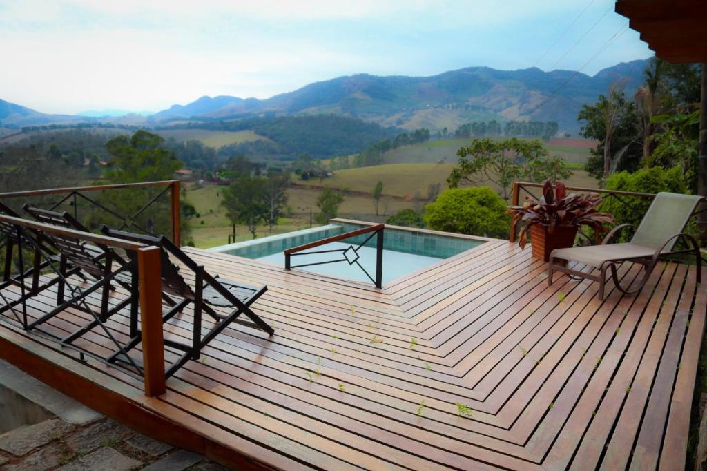 une terrasse en bois avec une piscine et 2 chaises. dans l'établissement Pousada Vidinha Bela, à Brazópolis