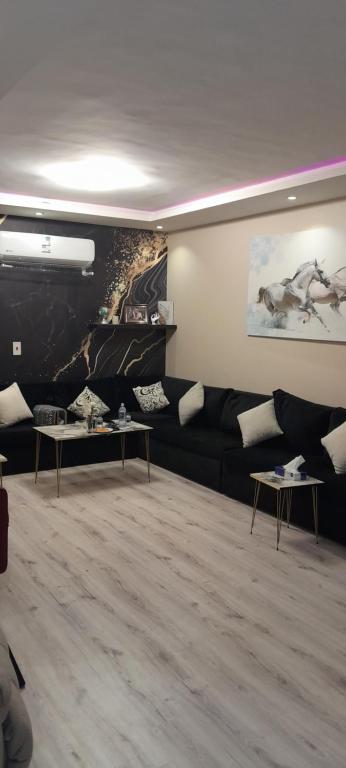 سهم نجد في الرياض: غرفة معيشة مع أريكة سوداء ولوحة خيول