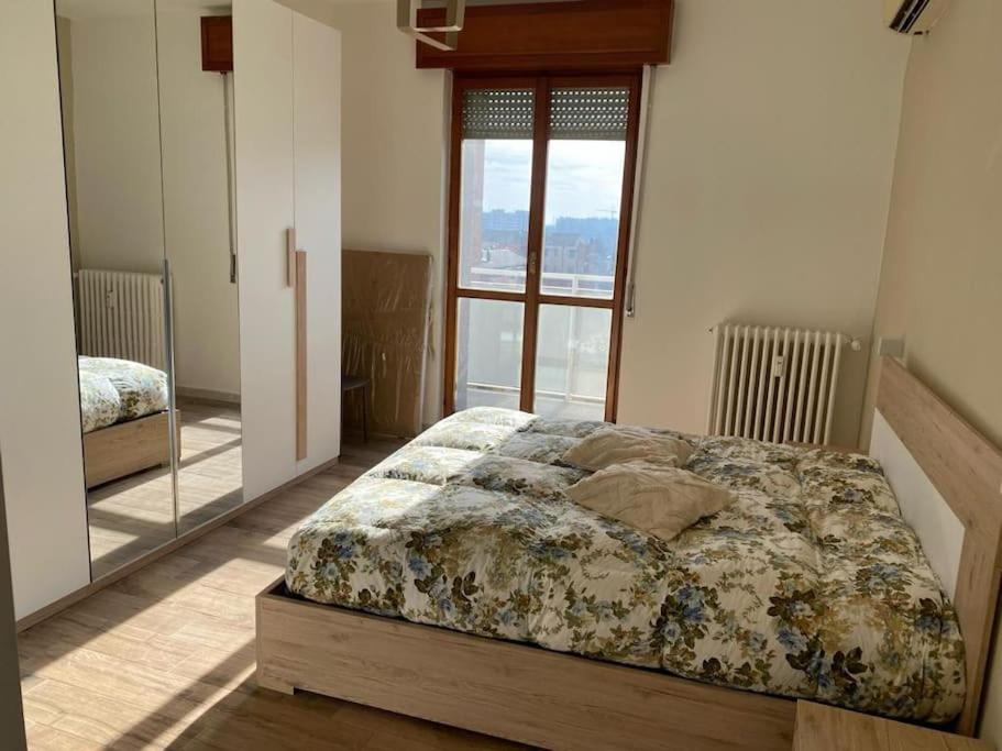 een slaapkamer met een bed en een grote spiegel bij CASA SAM - Luminoso e accogliente trilocale in Pioltello