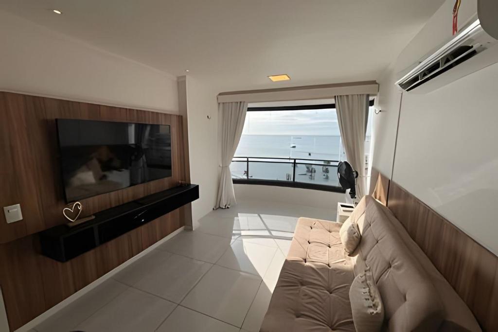 uma sala de estar com um sofá e uma televisão de ecrã plano em Hosts BR - Flat frente mar c/ cozinha em Fortaleza