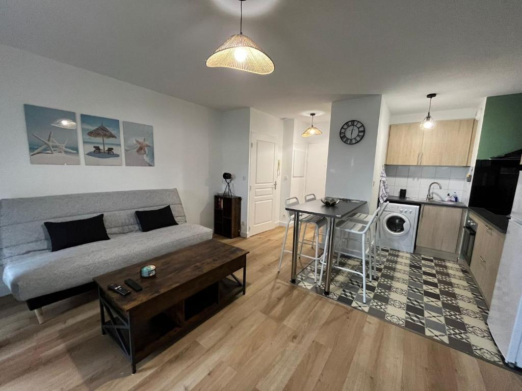un salon avec un canapé et une cuisine dans l'établissement Appartement avec jardin à Rochefort, à Rochefort