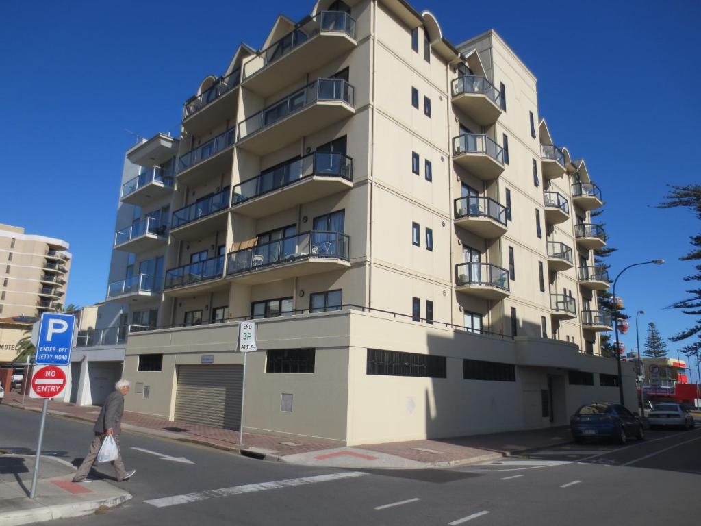 un hombre pasa por delante de un edificio de apartamentos alto en Holdfast Shores Apartments, en Adelaida