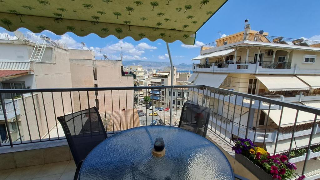 a table on a balcony with a view of a building at Tomis Sea View Apartment in Piraeus