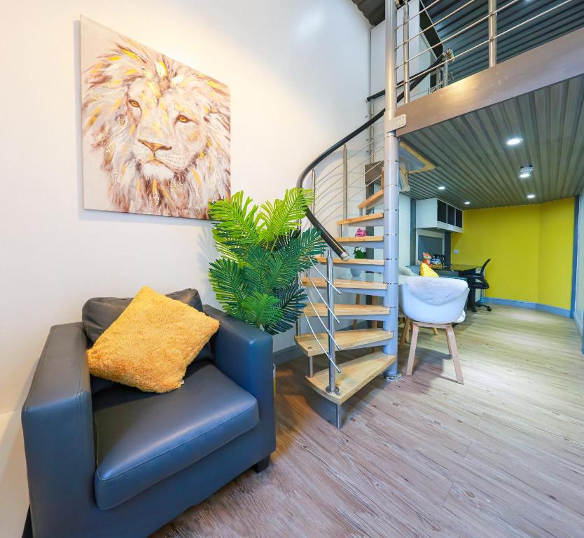 a living room with a blue chair and a staircase at E102 Urban loft vista in Coventry