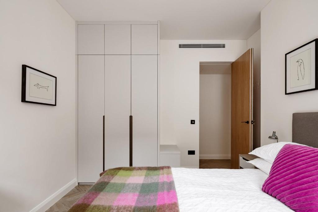 a bedroom with a white bed with a pink blanket at Modern Apartment & Rooms at Charing Cross in London
