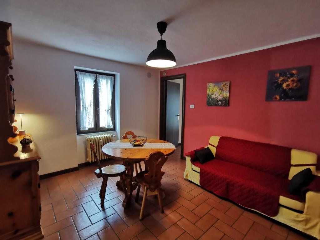 een woonkamer met een rode bank en een tafel bij Maison MayRose in Antey-Saint-André