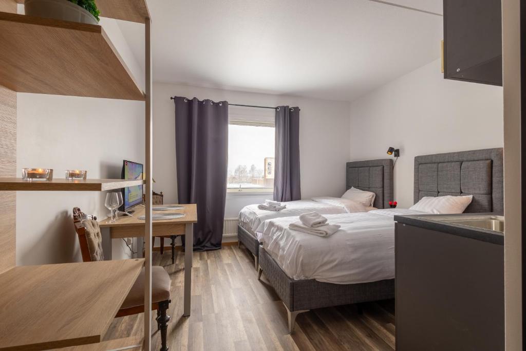 a hotel room with two beds and a desk and a kitchen at Halmstad Hotel Apartments in Halmstad