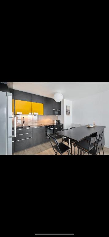 een keuken met een tafel en stoelen en een koelkast bij La Parisienne in Ivry-sur-Seine