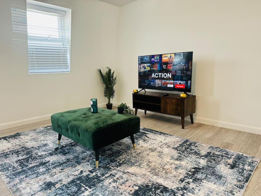 a living room with a television and a green ottoman at Unique spacious 2 bedroom Apartment 15 mins walk via tube to Central London in London