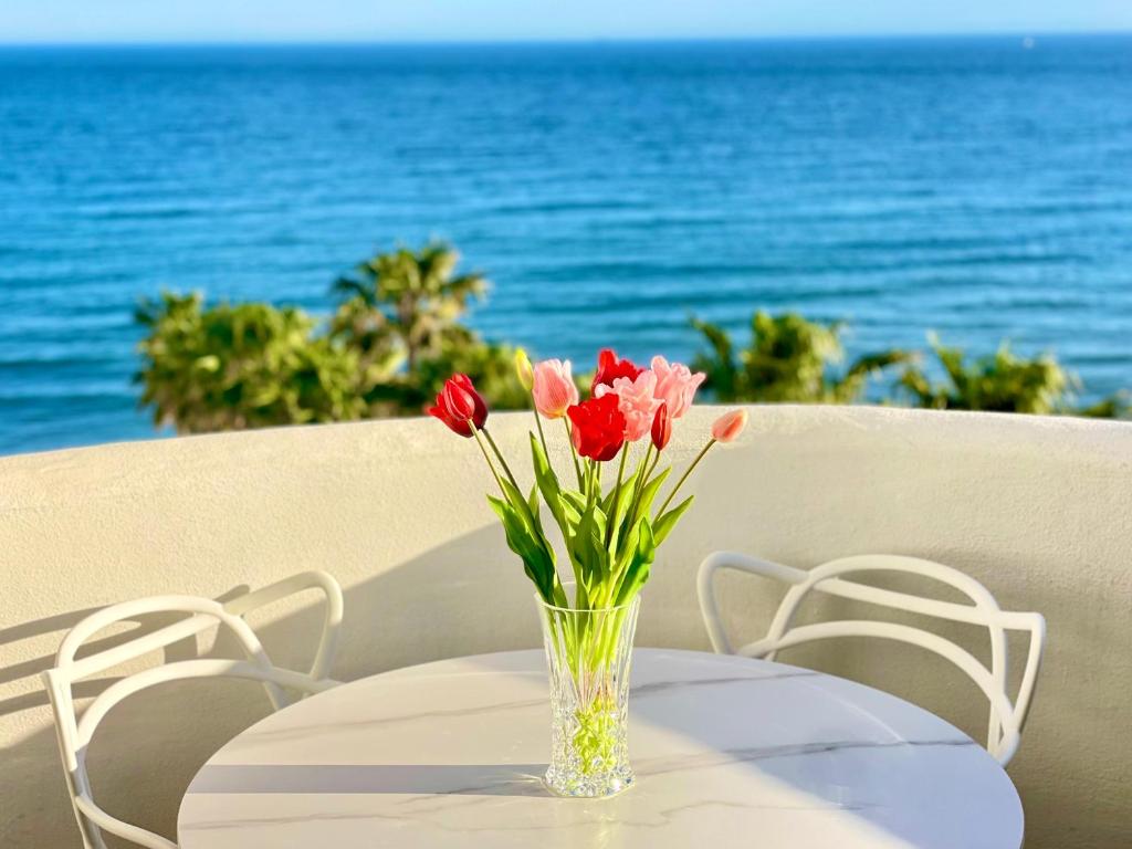 un jarrón de flores sentado en una mesa con el océano en Apartamento Algaida Calahonda, en Sitio de Calahonda