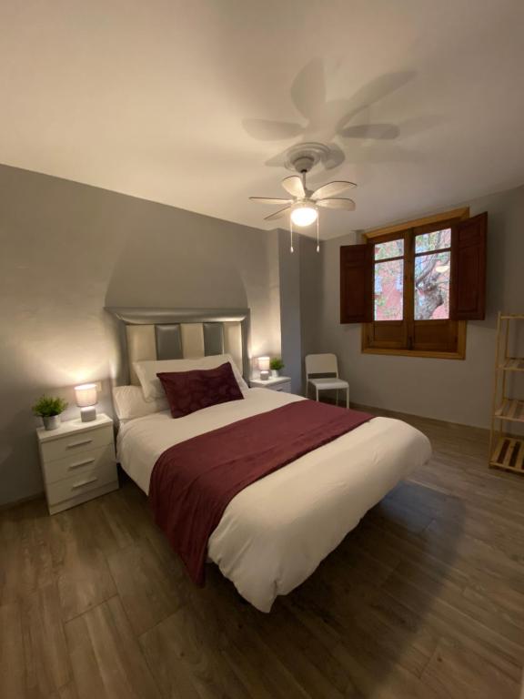 een slaapkamer met een groot bed en een plafondventilator bij Vitalba Apartments in Lanjarón