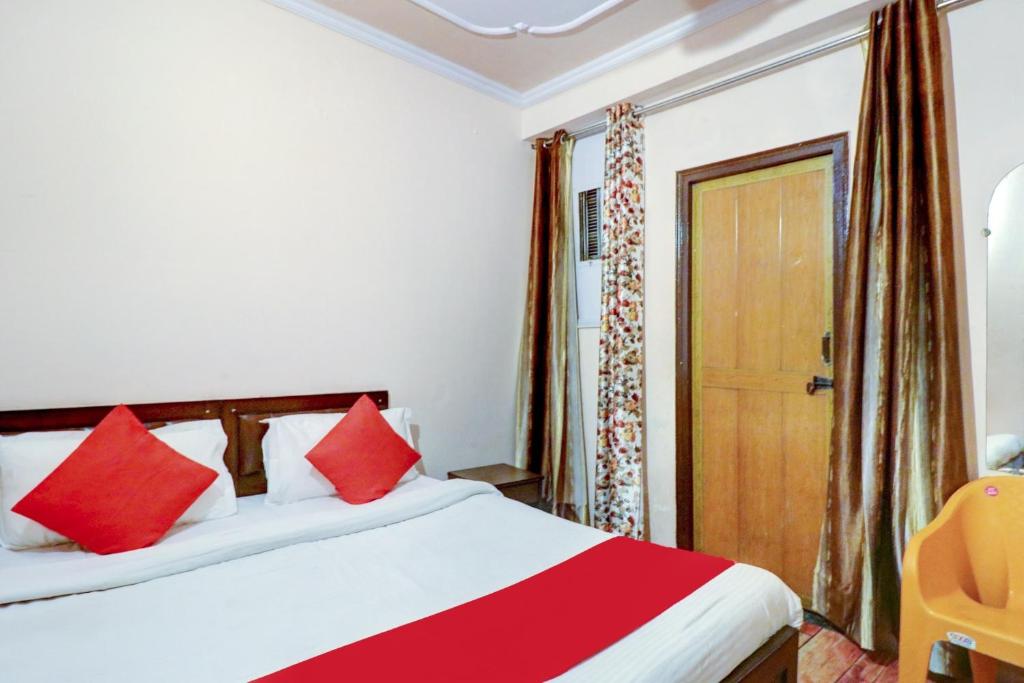 a bedroom with a bed with red and white pillows at Ratiram Hotel Near Worlds of Wonder in Kalkaji Devi
