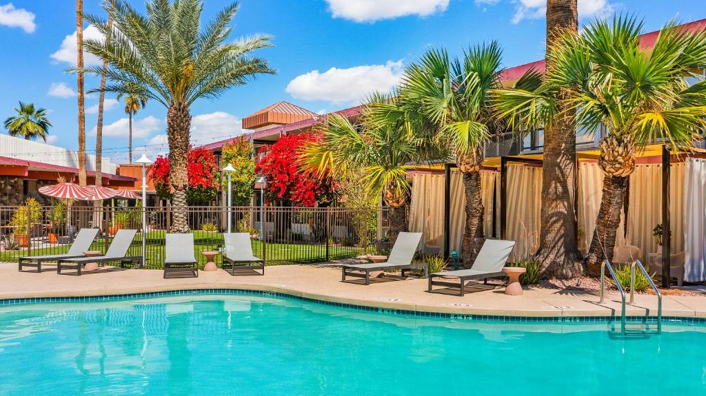 uma piscina com espreguiçadeiras e palmeiras em Papago Motor Hotel em Scottsdale
