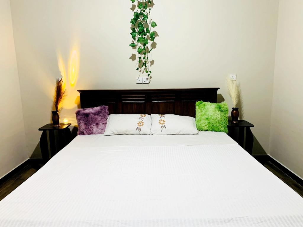 クルネーガラにあるSerene Stayのベッドルーム(大きな白いベッド、カラフルな枕付)