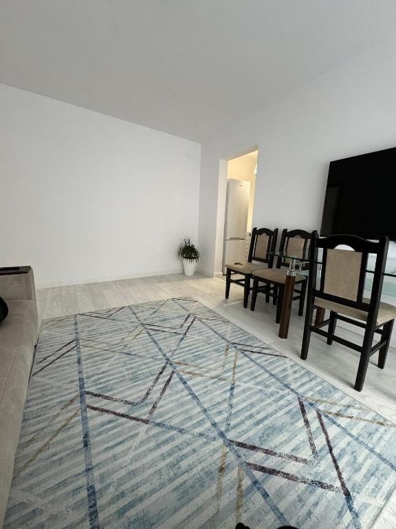 Habitación con mesa, sillas y alfombra. en Apartament Central en Râmnicu Vâlcea