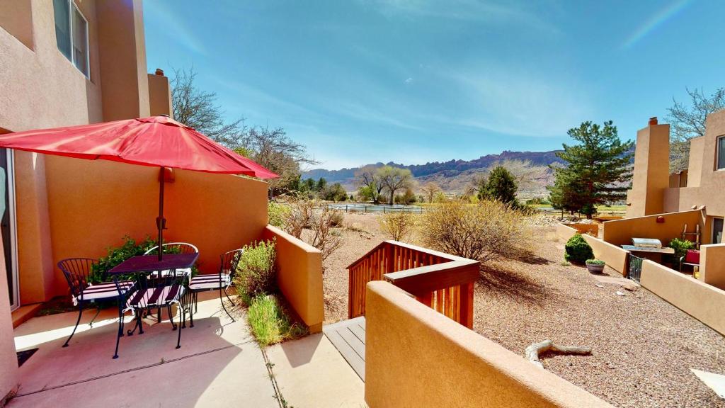 a patio with a red umbrella and a table and chairs at River Days #3326 in Moab