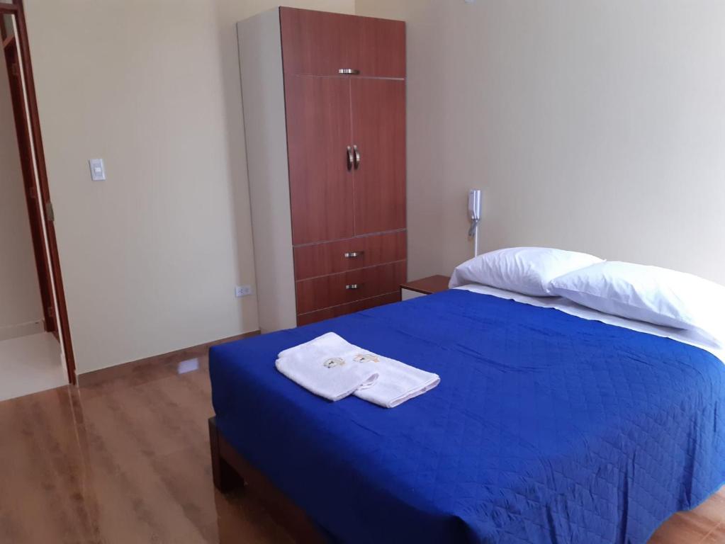 a bedroom with a blue bed with towels on it at Hotel Samanahuasi nasca in Nazca