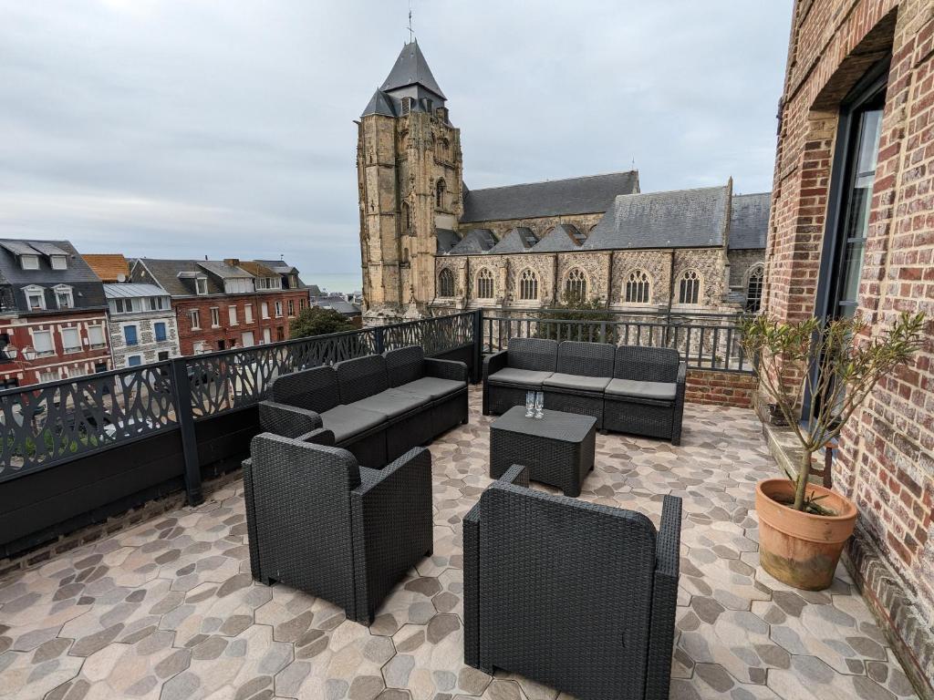 Il dispose d'une terrasse dotée d'un mobilier noir et d'un balcon avec un bâtiment. dans l'établissement Maison Côté Mer, au Tréport