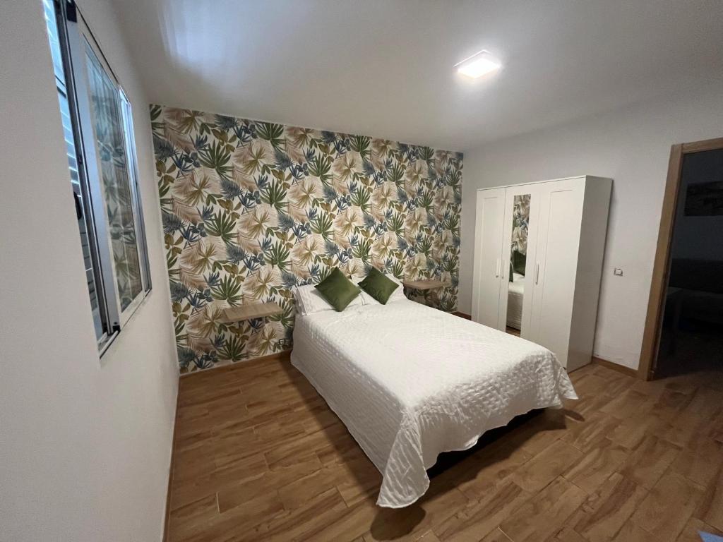 1 dormitorio con 1 cama y papel pintado con motivos florales en Paraíso Playa de Arinaga en Arinaga