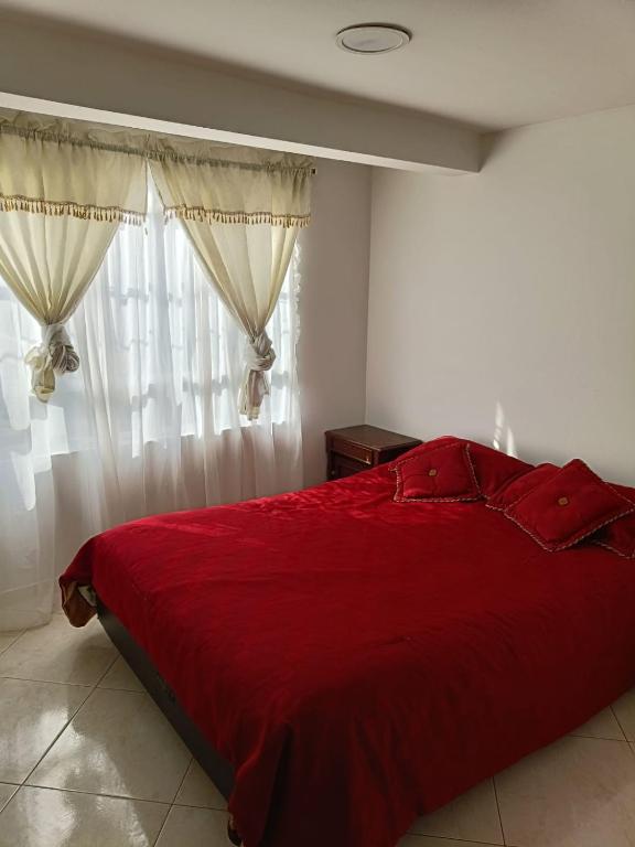 ein Schlafzimmer mit einem roten Bett und einem Fenster in der Unterkunft San antonio urbano in Bogotá